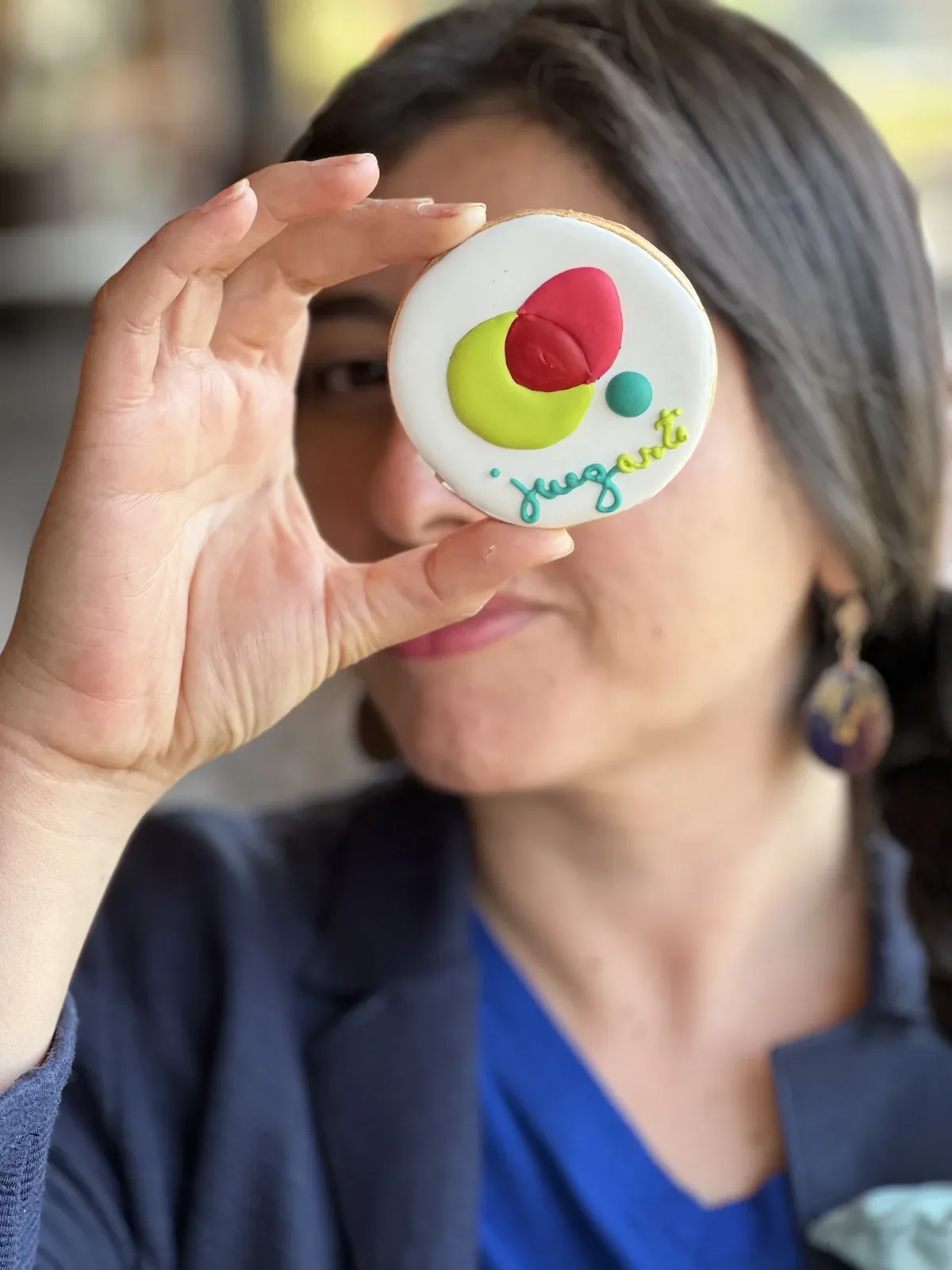 Persona sosteniendo un pin de Juegarte frente a su ojo