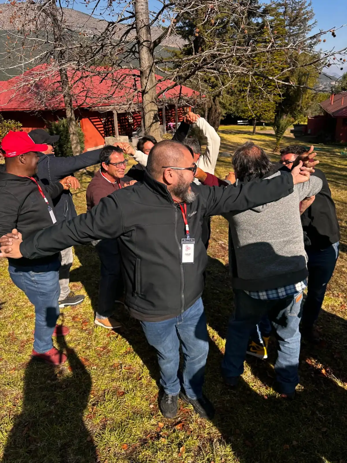 Grupo de personas en círculo con los brazos abiertos en un parque