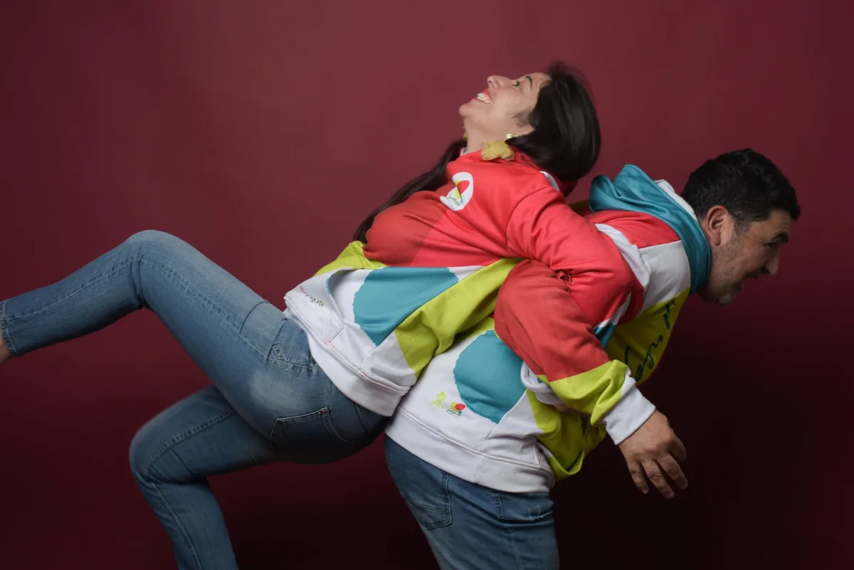 Dos integrantes de Juegarte en una pose de juego sobre fondo granate